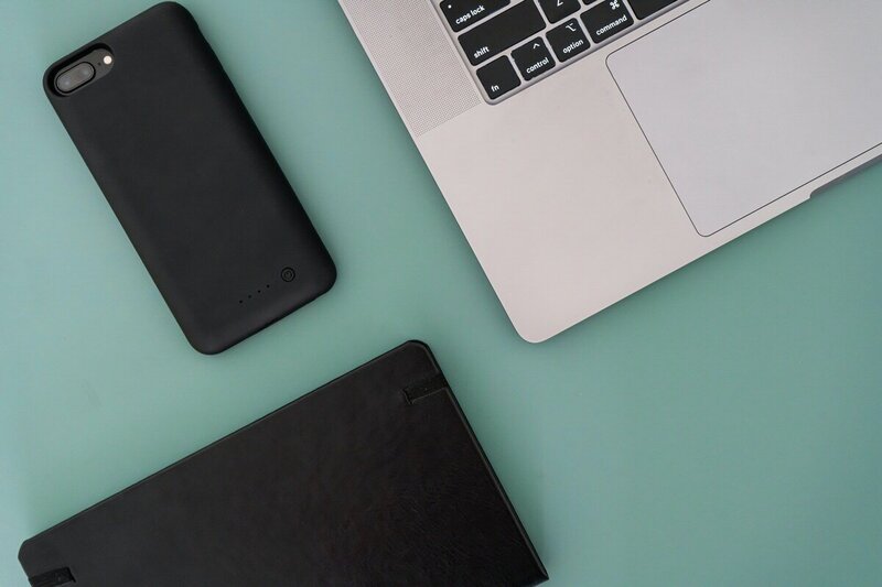 laptop phone and notebook on blue background