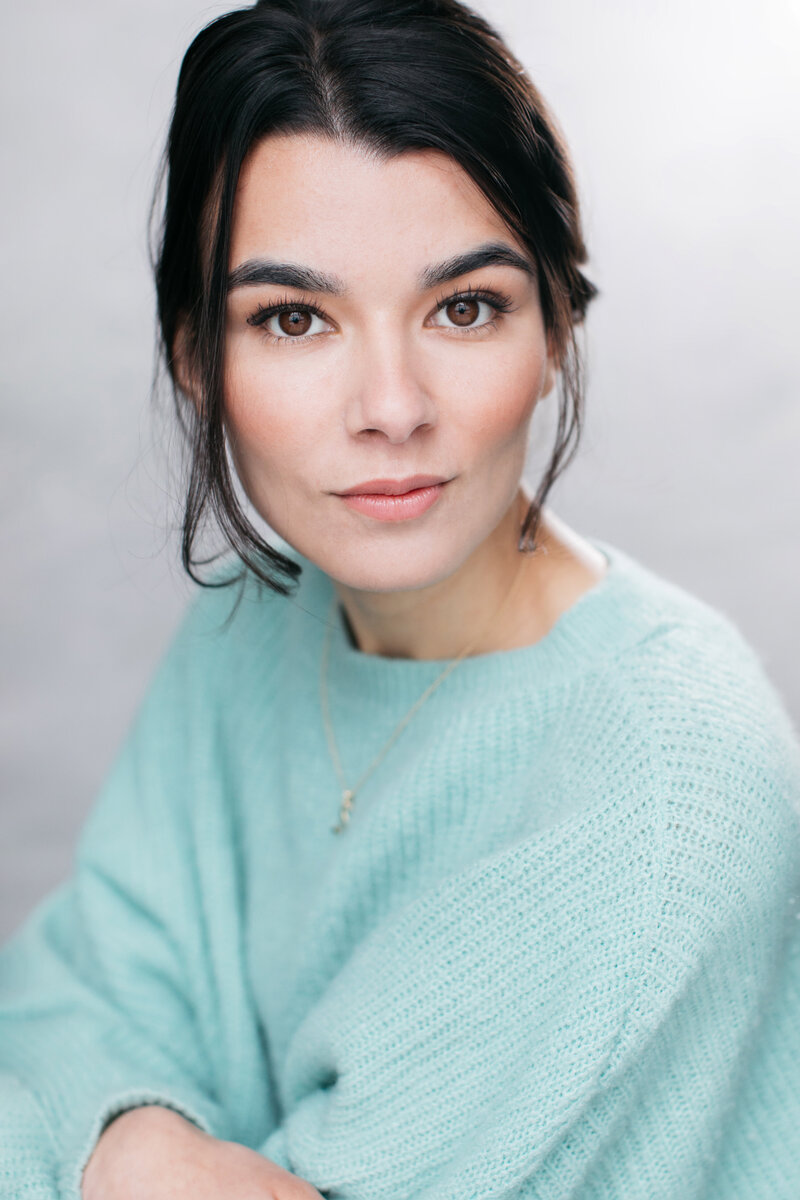 Castingfoto van musicalster met mintgroene trui, donker haar en een krachtige blik.
