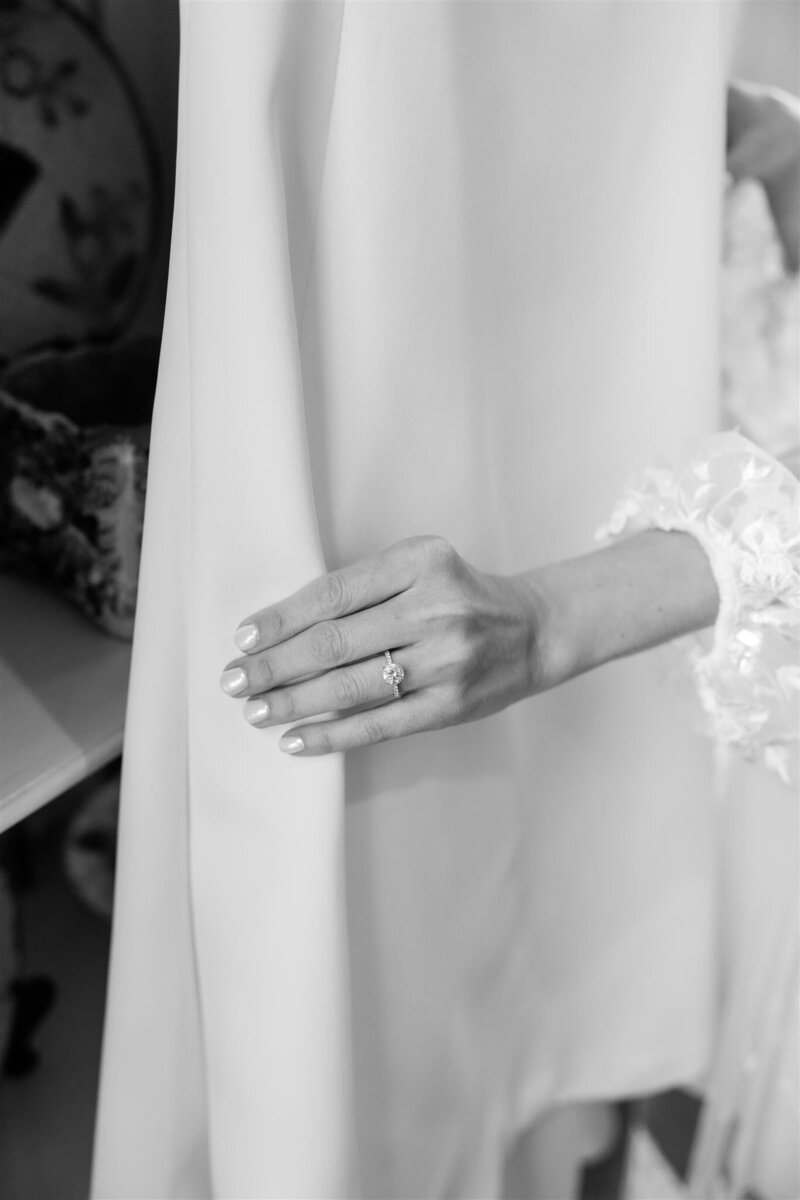 A black and white photo of the bride's ring hand on her wedding dress by Florida wedding photographer. 