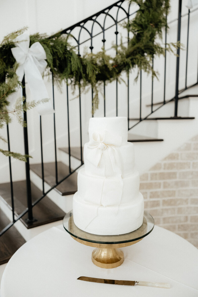 An elegant four tier white wedding cake on a gold pedestal.