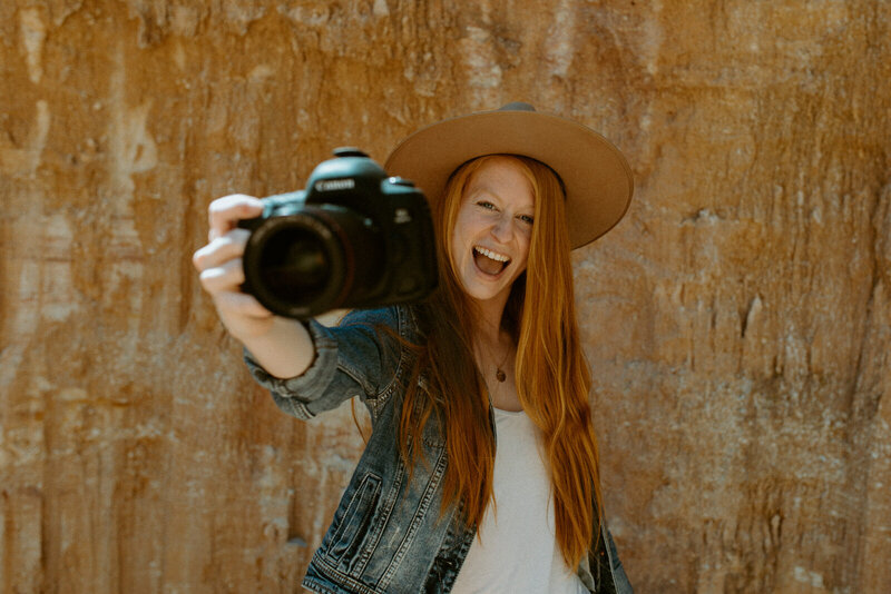 woman wearing a hat and smiling while holding camera