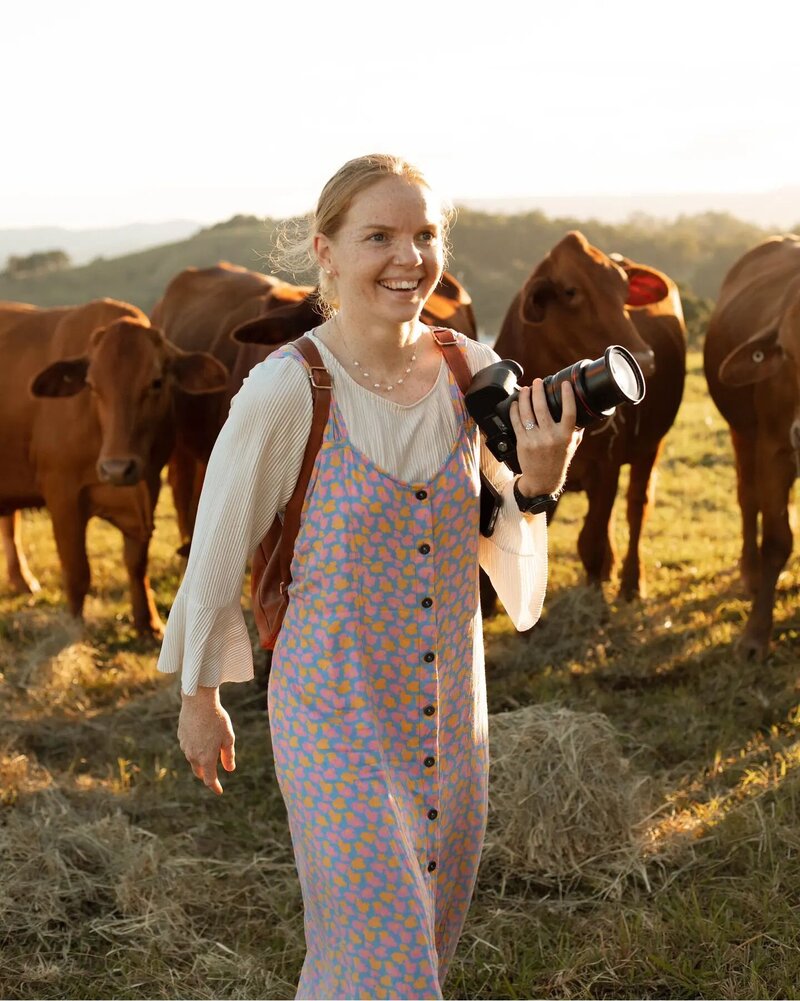 Your Neck of the Woods Photographer, Scout, standing with some cows holding a camera