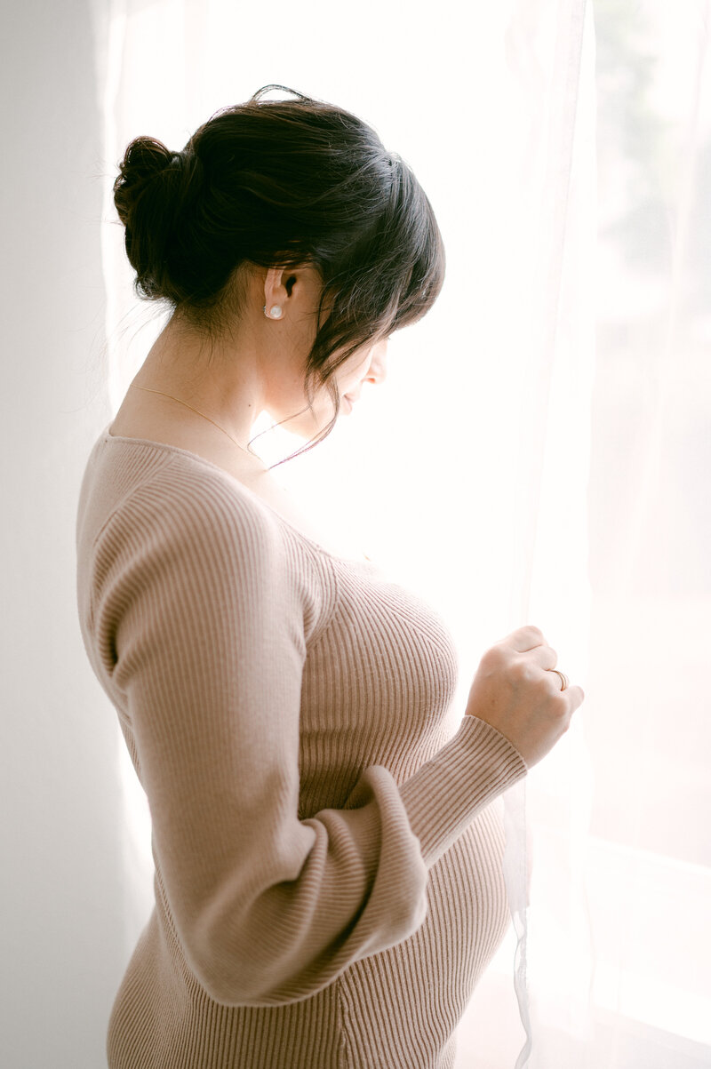 Pregnant mom looking out the window during maternity session
