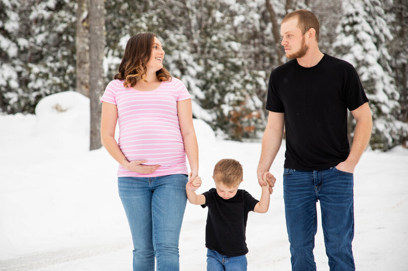 Family walking in snow holding hands, Mom is holding pregnant belly too | Family Photography Session in the snow