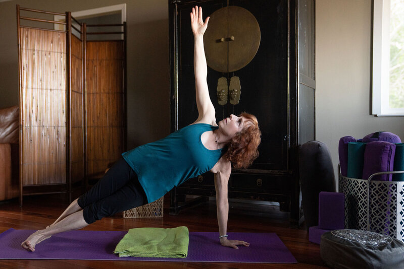 Woman on yoga mat with arm stretched out towards the ceiling