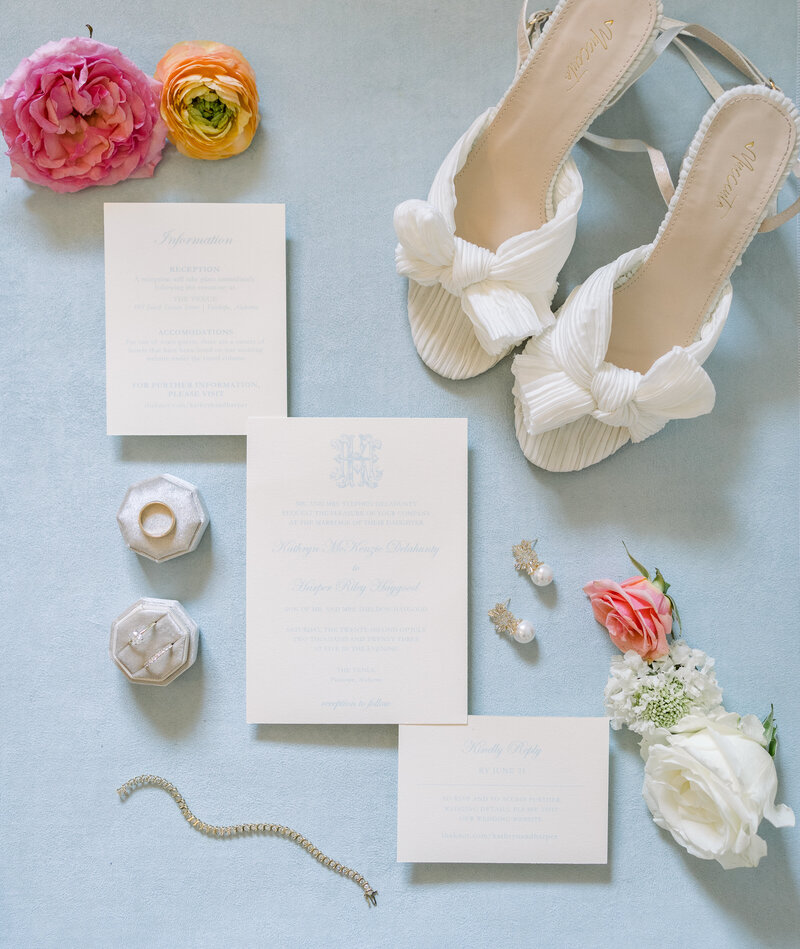 flat lay of wedding stationery, colorful florals, bridal shoes, and other wedding details