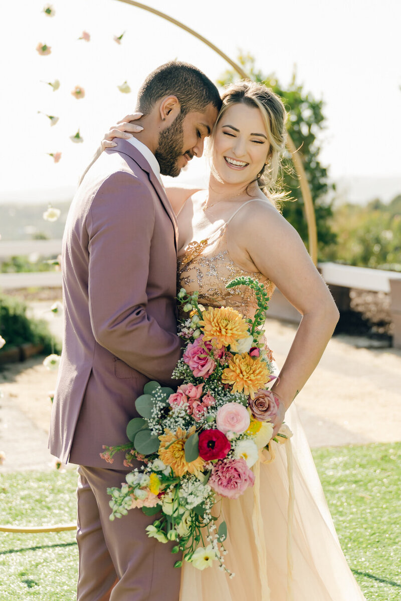 bride and groom embracing while smiling 