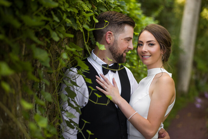 Groom gazing at his new bride during portraits at their Winterthur Gardens elopement, surrounded by lush greenery.