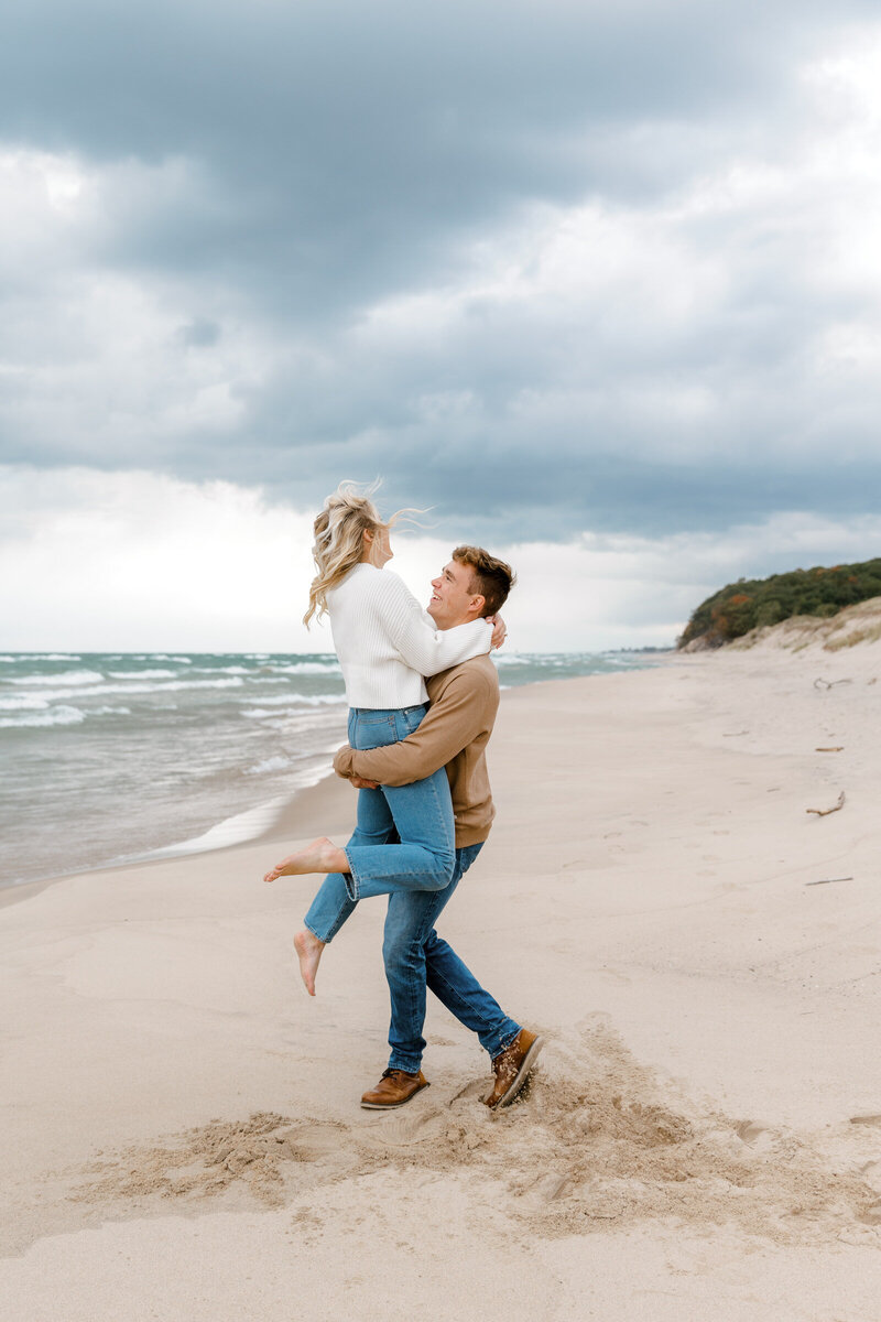 couple playfully spinning on the beach of lake michigan lindsay elaine photography