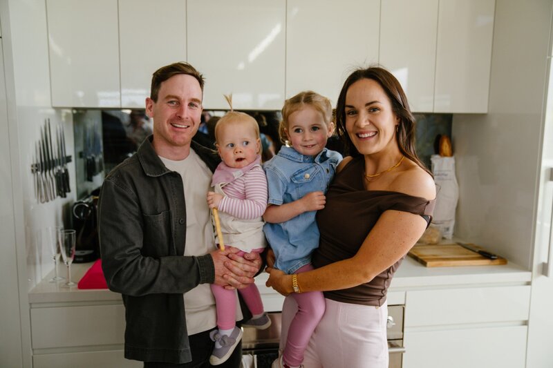 Brent, Isabelle McNeil and their Daughter smiling in front of their custom home