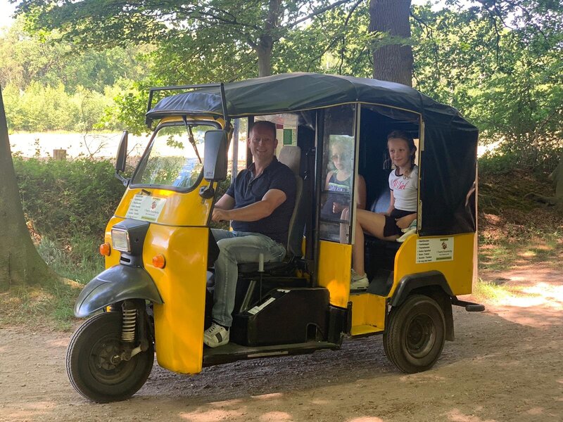 Man bestuurt gele TukTuk met passagier tijdens een tocht – geschikt als gezinsactiviteit of origineel bedrijfsuitje.