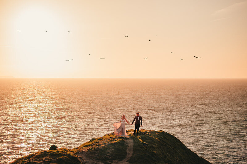 couple hold hands overlooking the ocean