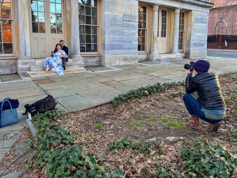 A behind-the-scenes moment during an engagement session at Second Bank, featuring a couple in a relaxed, seated pose against the historic architecture, capturing the timeless charm and ease of their love story.