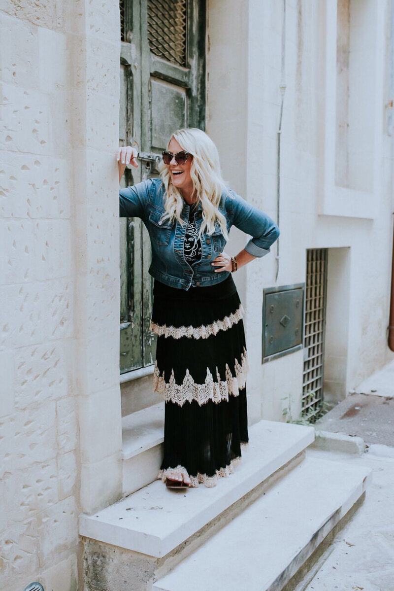 Chrissy Gilmartin, a wedding photographer, leans on a door sill on an old rustic building