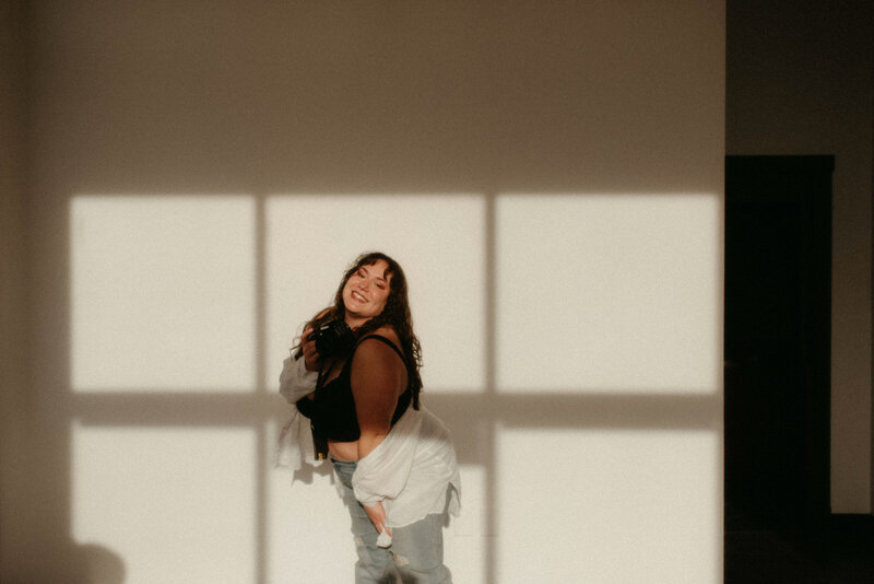 Taeya sitting in a chair laughing and holding her camera
