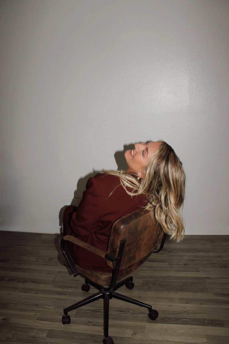 The founder of The Aesthetic Edit leans back in her chair, laughing with genuine joy. This image captures the passionate and inspired spirit behind the aesthetic website design and marketing strategies offered by the San Diego-based company.