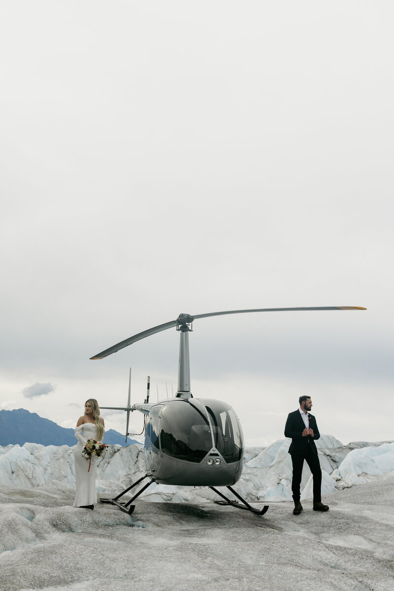 A couple standing next to a helicopter. 