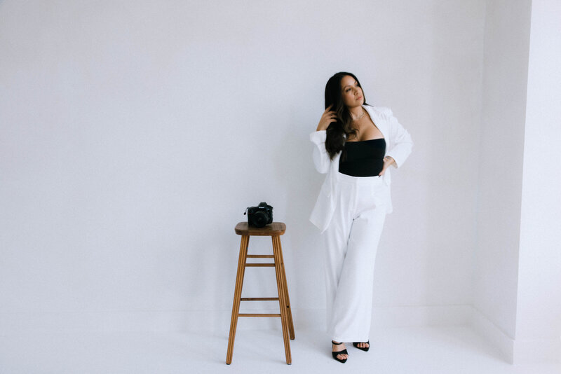 Rachael Marie, Seattle wedding photographer, lying in grass wearing a white blouse and hat, capturing relaxed and natural bridal portrait style