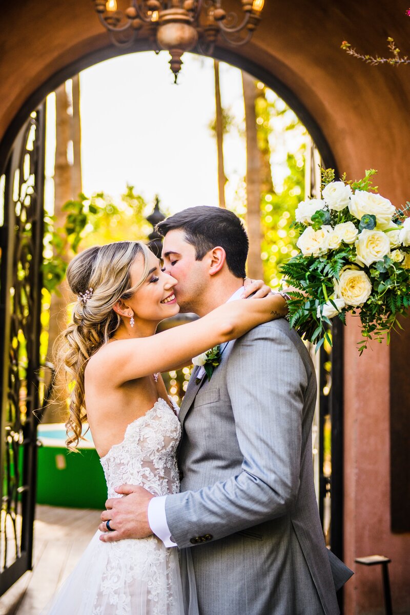 Groom kissing brides cheek at Boojum Tree hidden gardens wedding Scottsdale