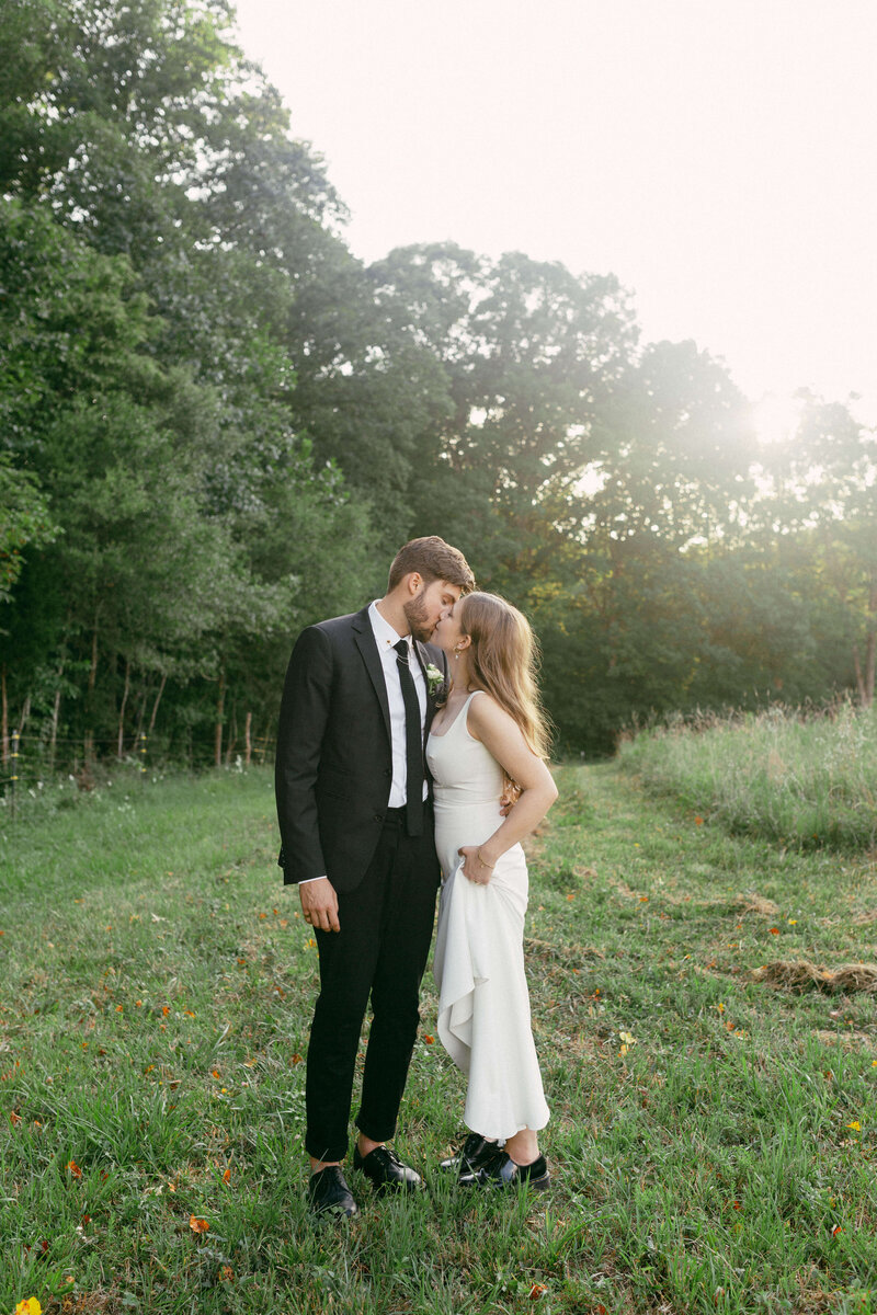 The couple shares a kiss in their wedding attire during a classic outdoor wedding session