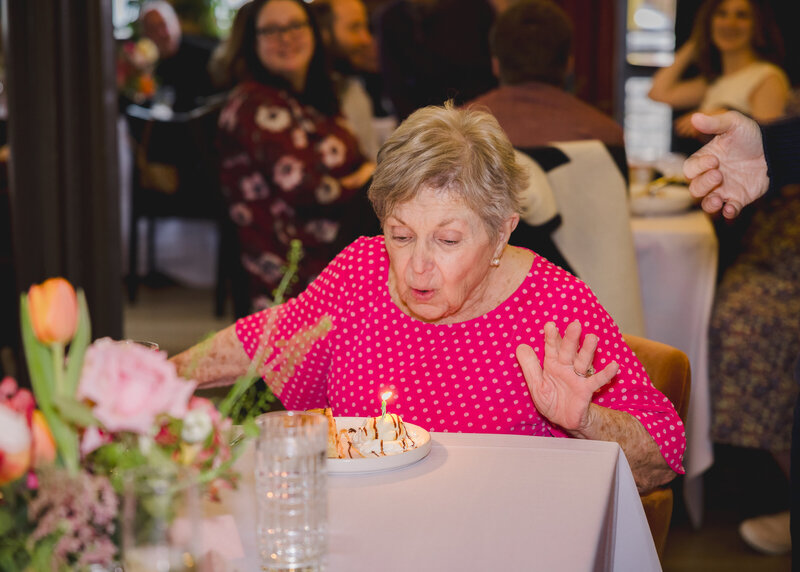 Grandmother blowing out her candles at a milestone birthday party in NJ