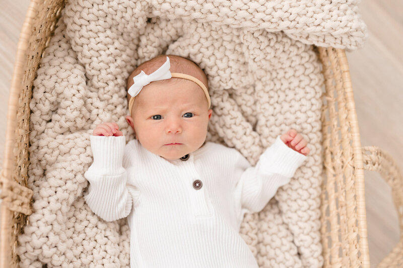 Newborn baby girl laying in a basket during her newborn photography session