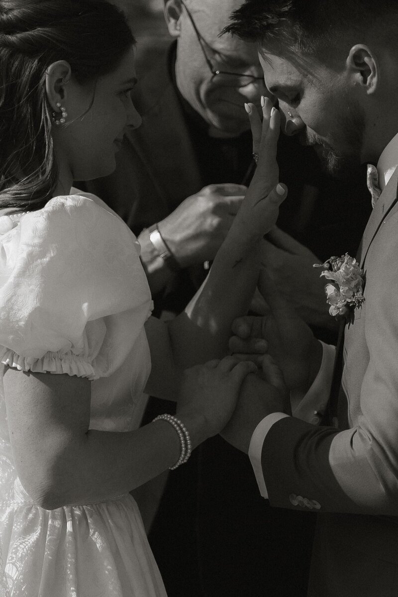Sentimental moment as the bride tenderly wipes away tears from groom's face during ceremony.