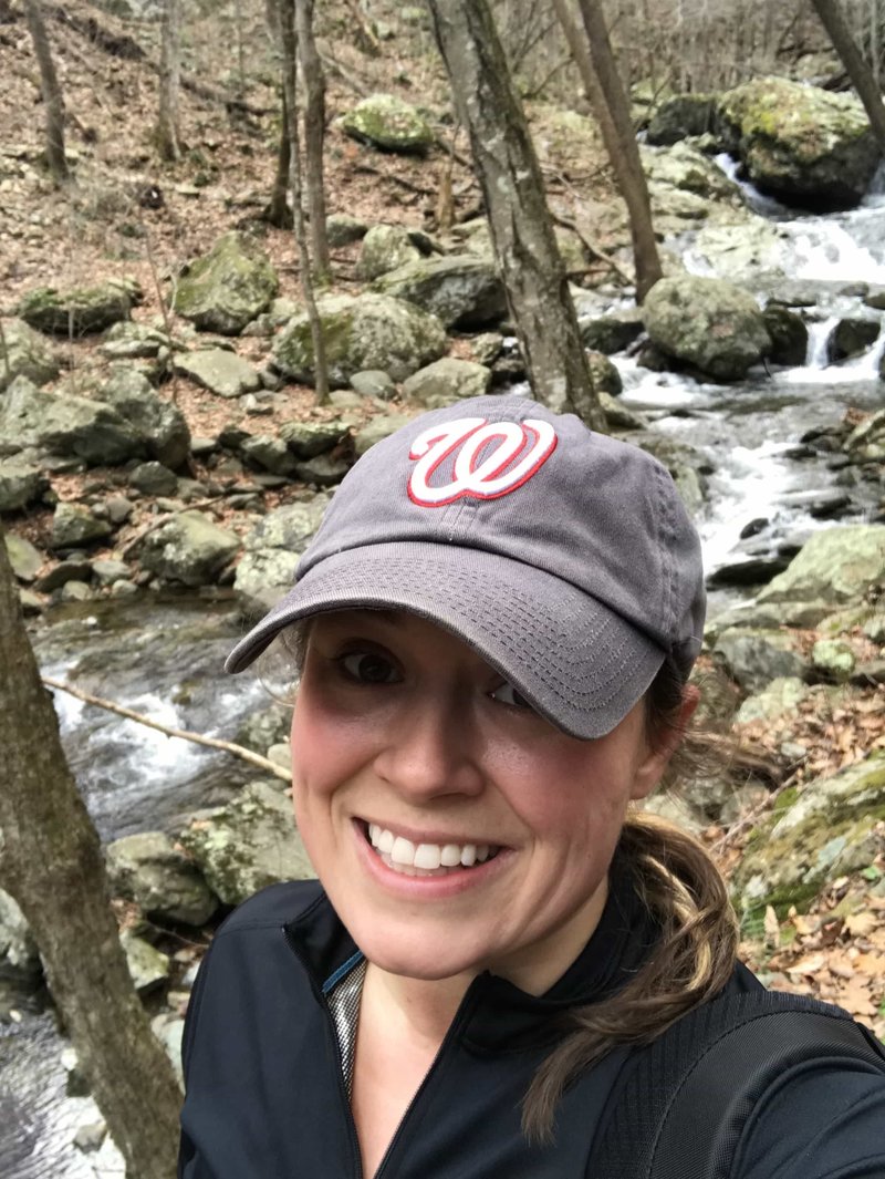 A woman with a baseball cap on out in nature