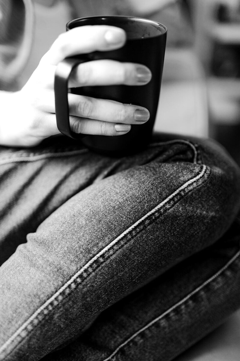 Black and white photo of Andrea holding a black mug