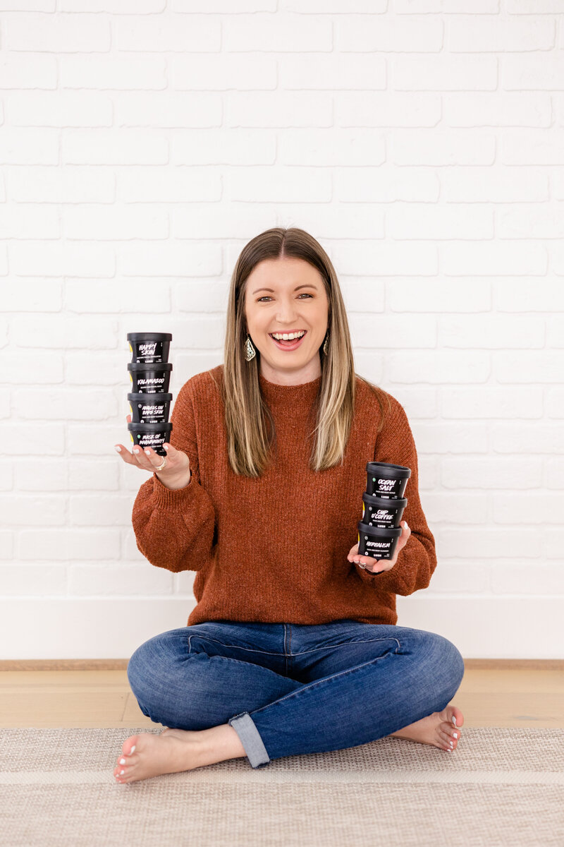 Girl holding Lush pods and laughing while sitting on the floor