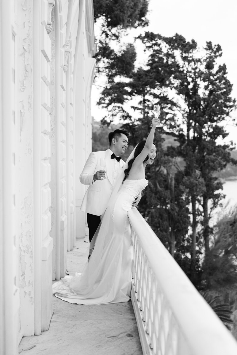 bride and groom on balcony and toasting to crowds below