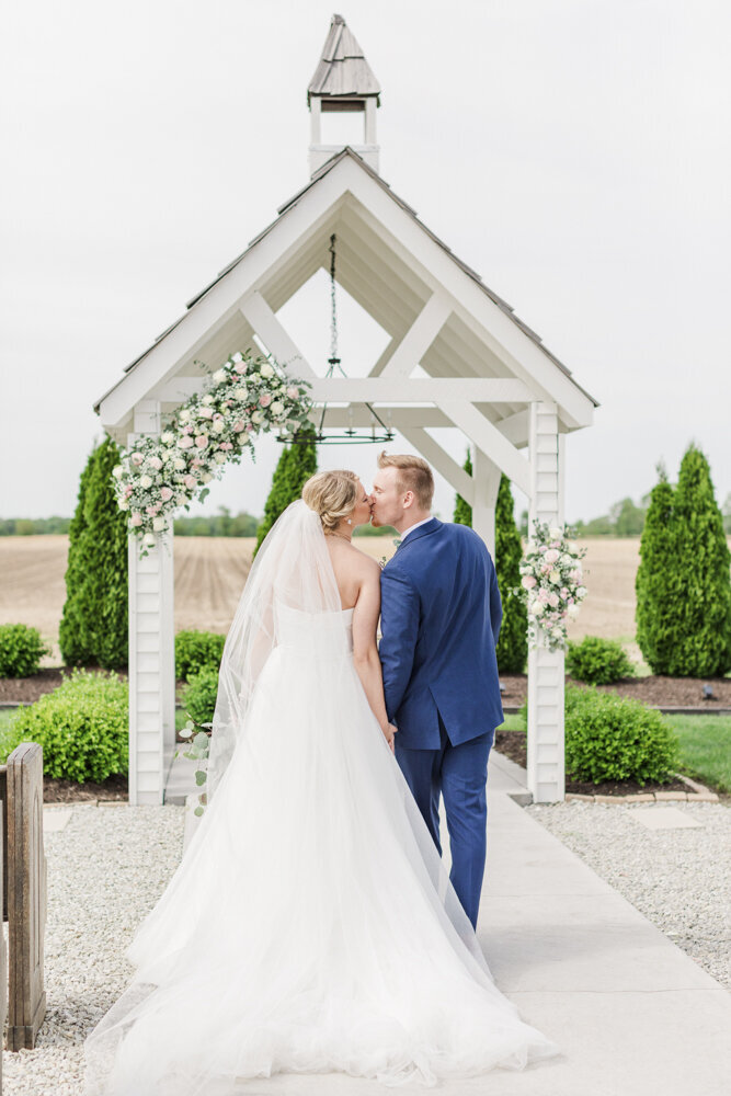 bride and groom kissing at a beautifully landscaped wedding venue