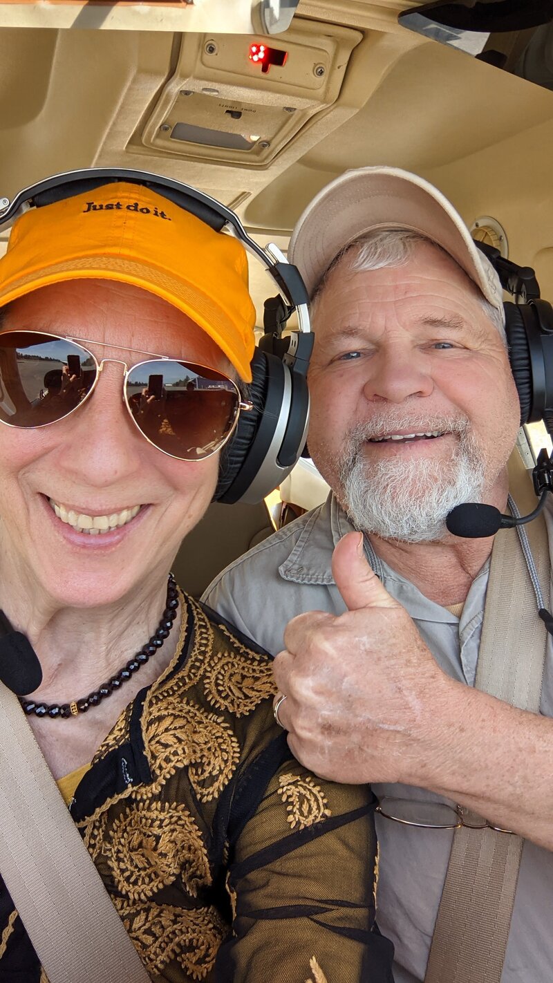 Barbara and Patrick in a plane flying over Brookings giving a thumbs up