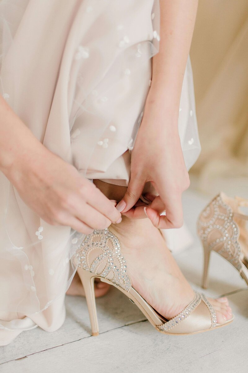 Lower shot of bride adjusting her nude diamond heel strap