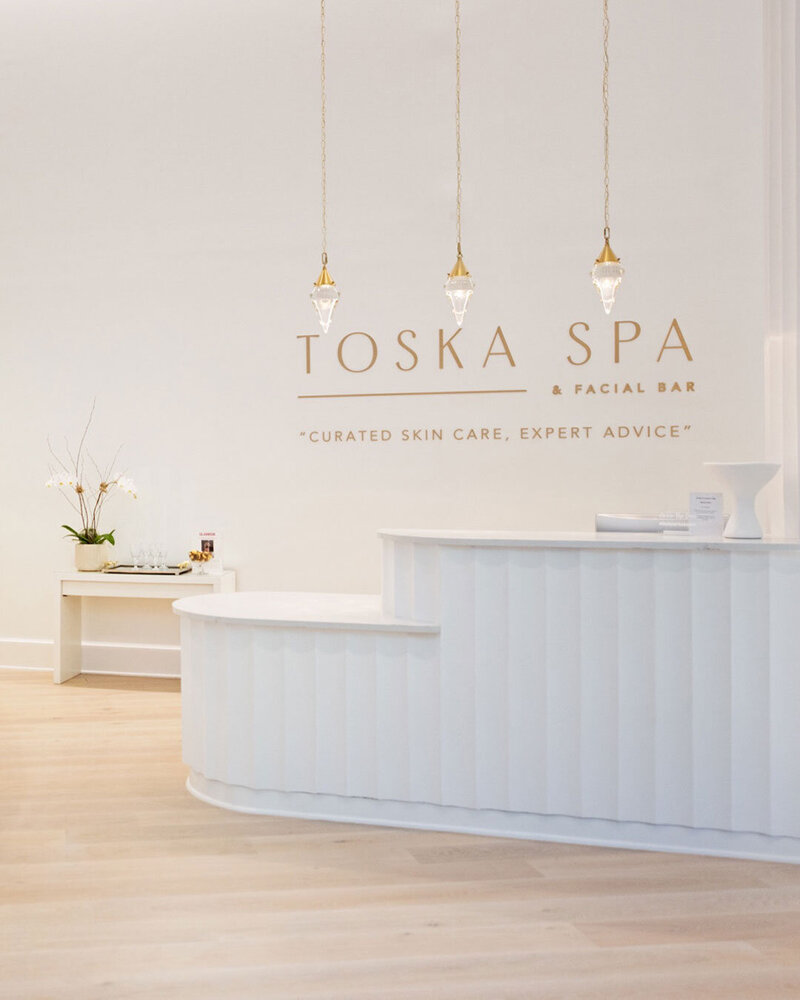 Light, airy spa interior with Toska Spa brand signage and minimalist design aesthetic