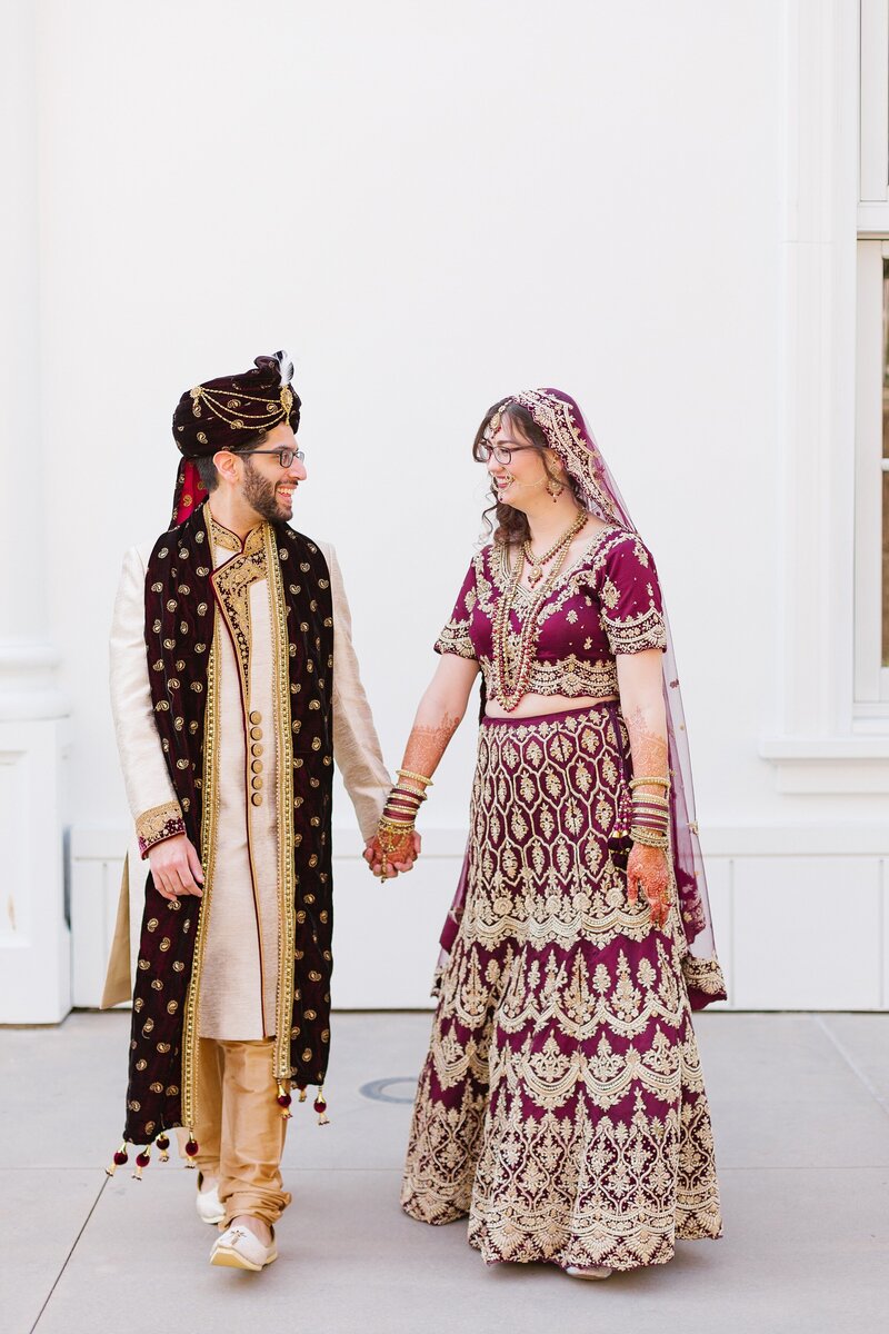 couple in hindu wedding attire holds hands outside the Richard Nixon Library in Yorba Linda, CA