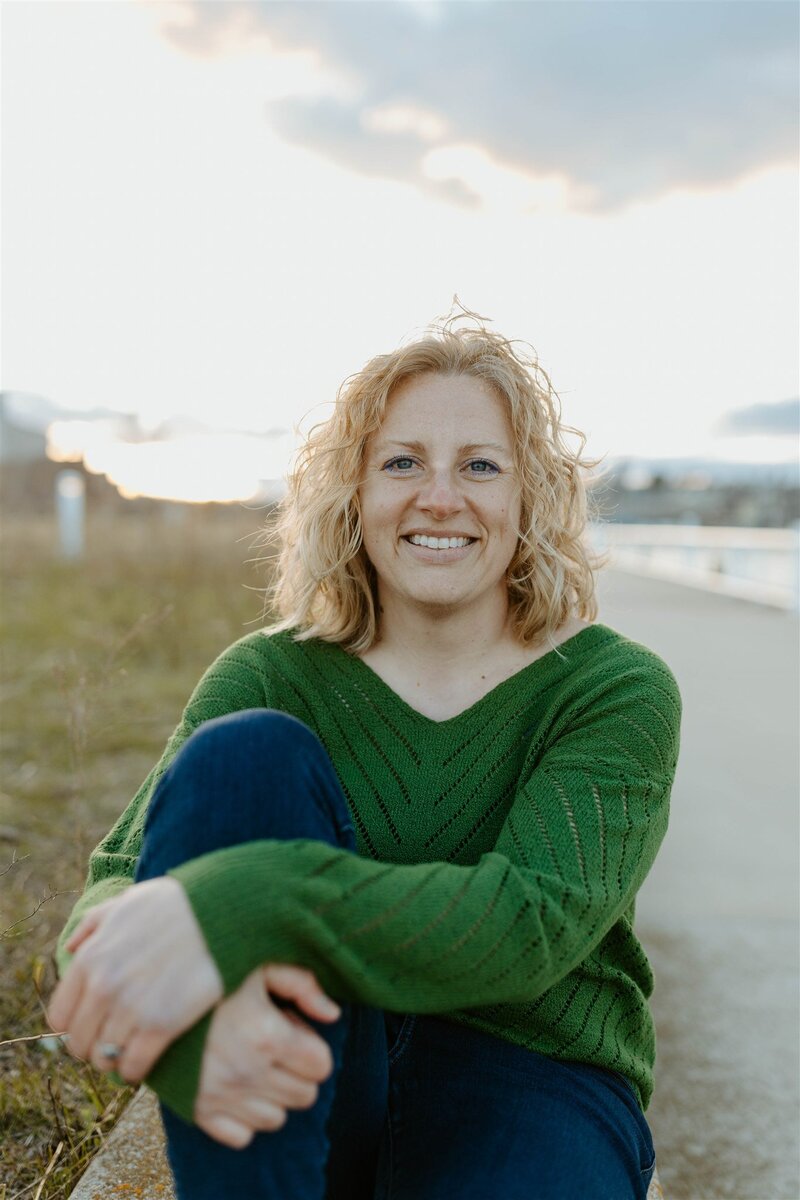 Writer, Sarah Freymuth, looks off to the side outdoors in black v-neck t-shirt