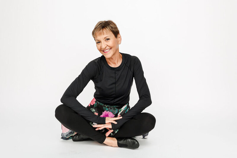Melinda Fornero in black shirt with floral skirt sitting cross legged