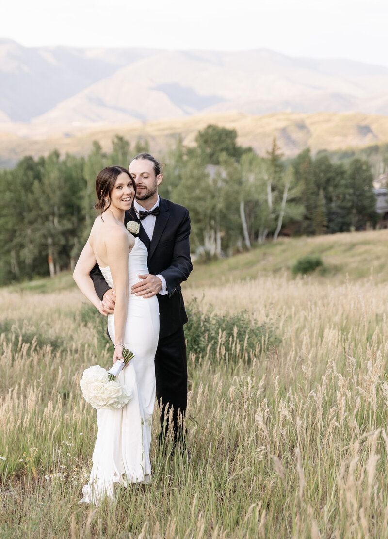 A beautiful bride holds her bouquet and has a cowboy hat on for her aspen, colorado wedding,