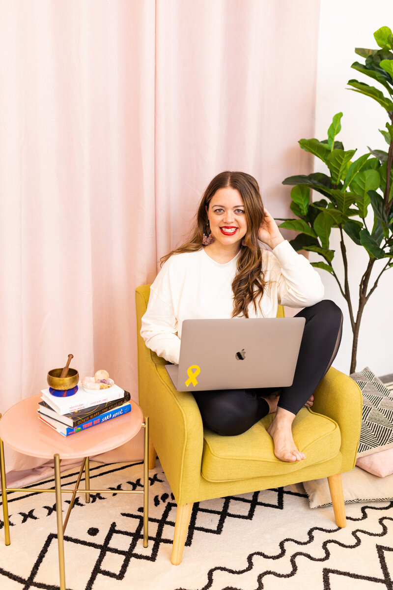 heather smiling in yellow chair with laptop
