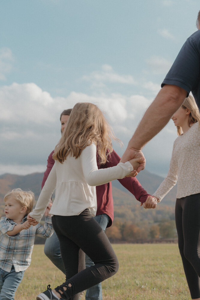 A family of five plays ring around the rosey together at Chestnut Ridge Farm in Limestone, TN