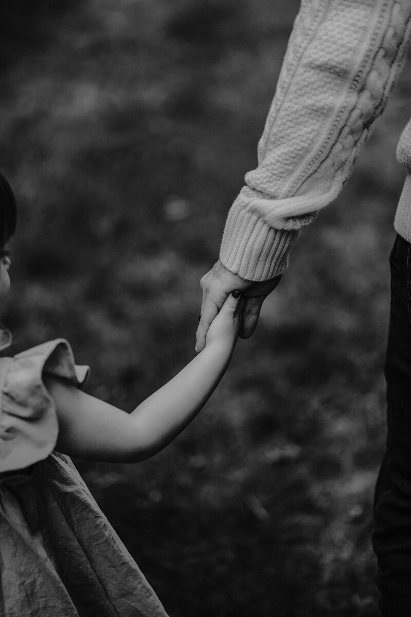 Outdoor candid lifestyle photography of dad holding hands with daughter