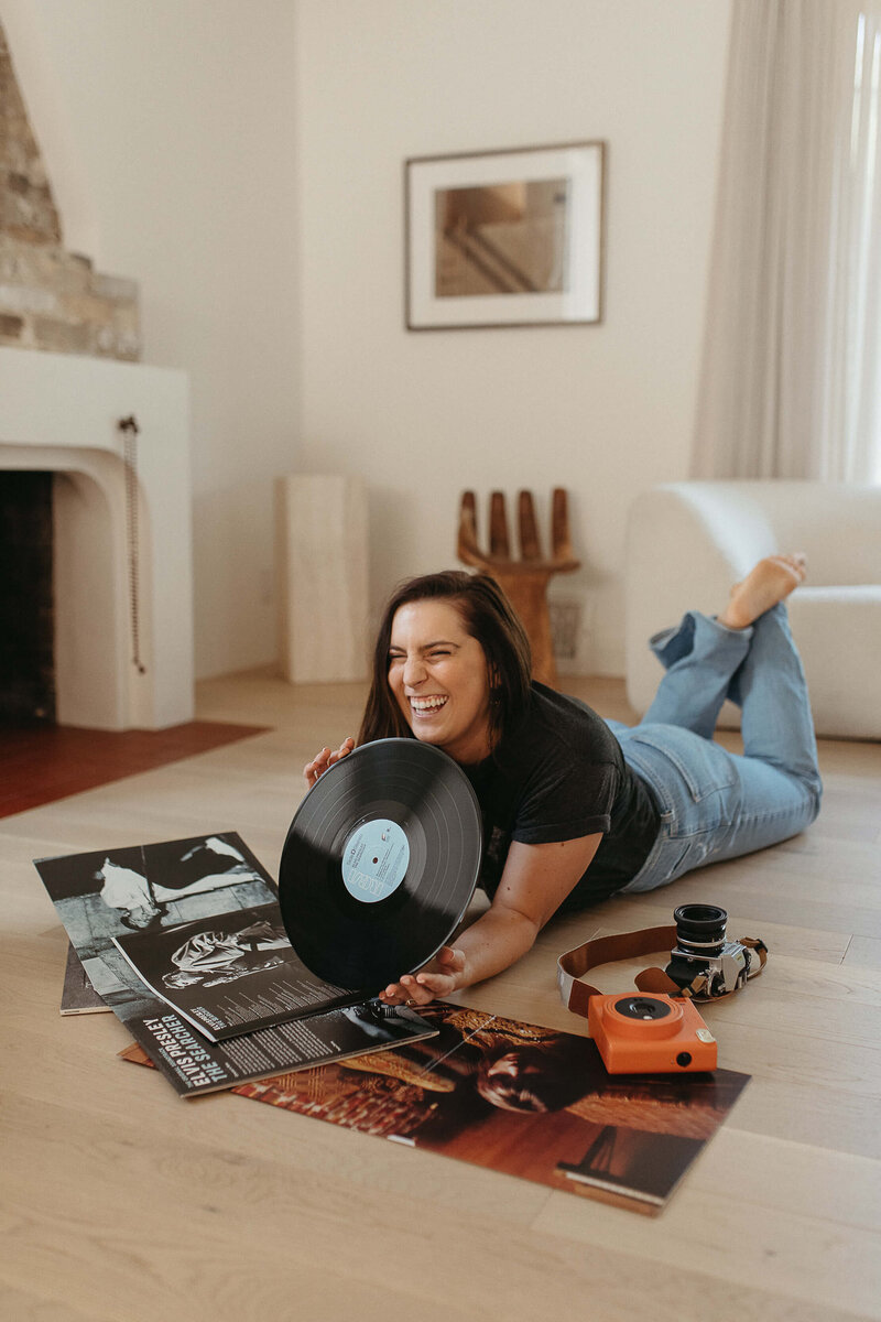 Photographer lays with vinyl records and film cameras