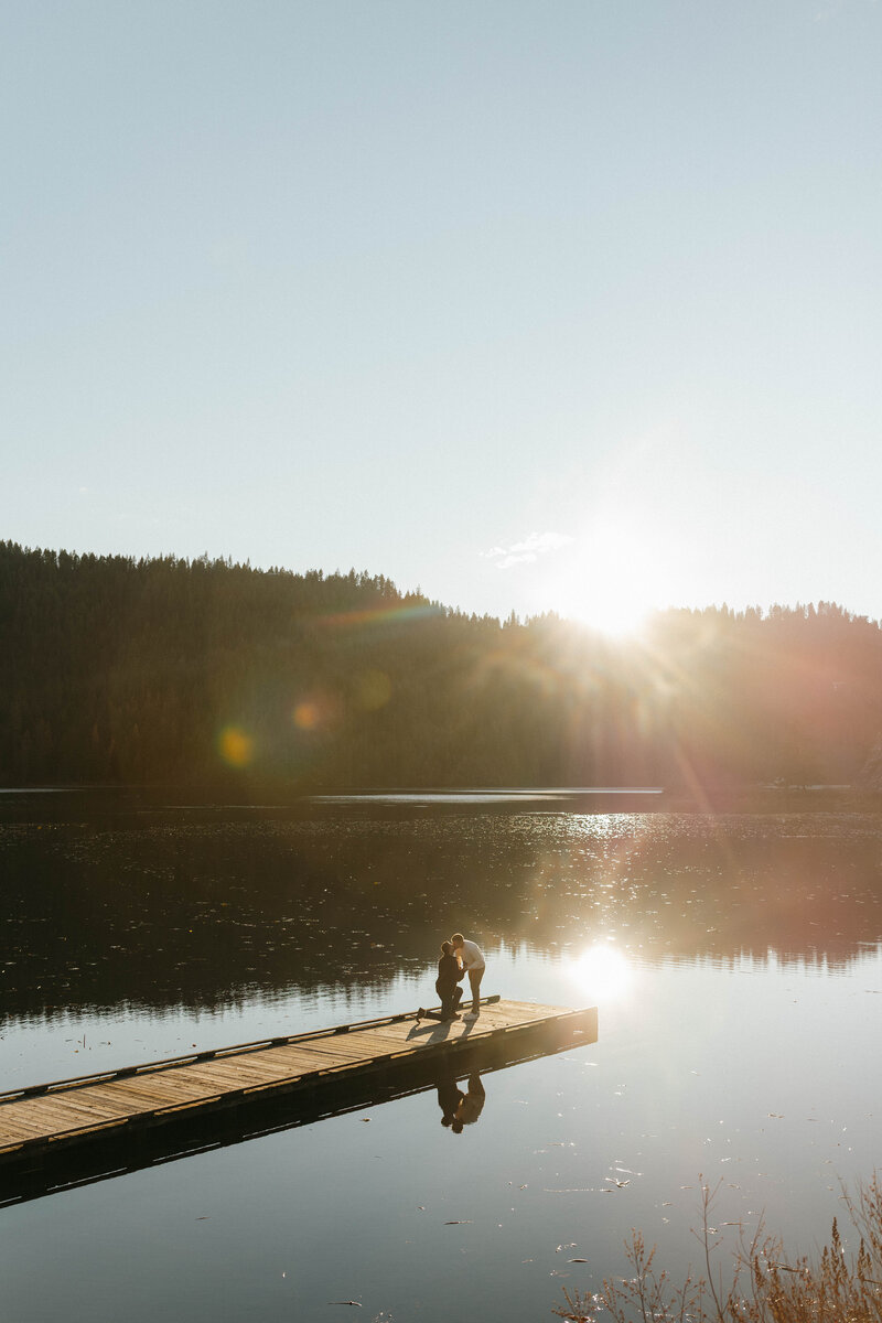 lgbtq+ couple getting engaged on lake in pacific northwest at golden hour