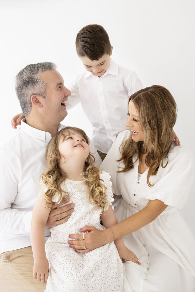Candid family photography Melbourne with parents and children laughing together in studio