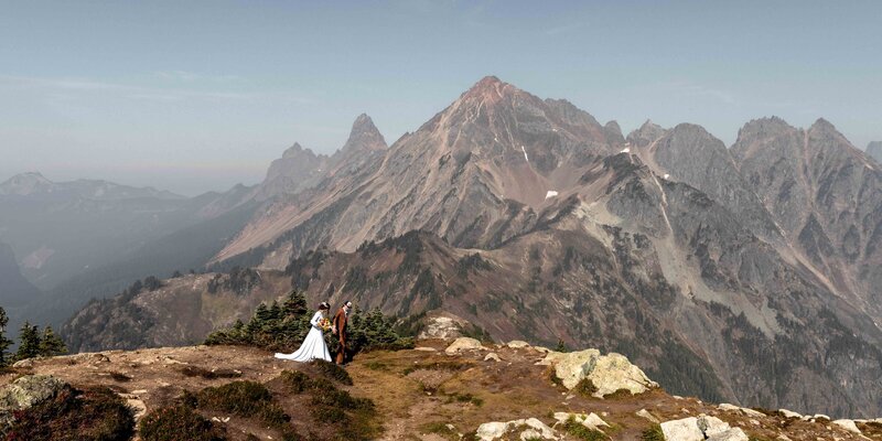 A wedding couple walking on a ridge with a big mountain behind in the North Cascades