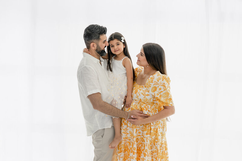 Couple holding daughter between them during soft light maternity session  — photographed by Alliston and Barrie maternity, newborn, and family photographer.