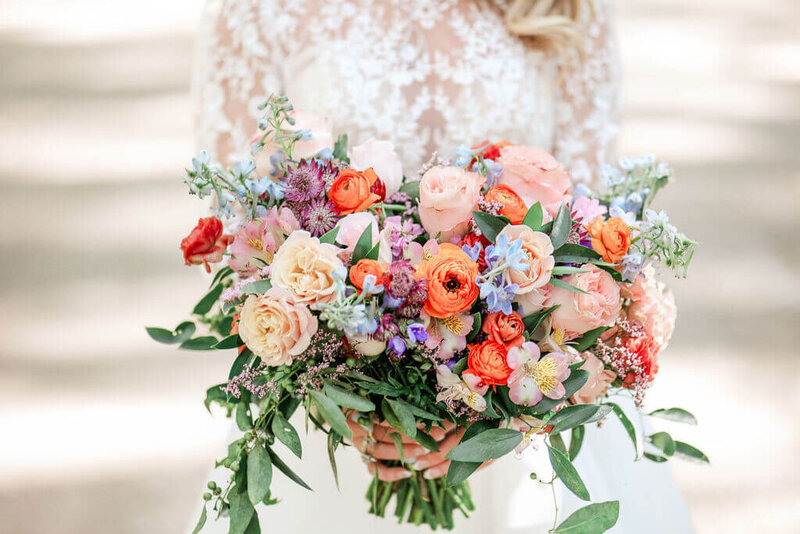 A vibrant bridal bouquet with orange, pink, and purple flowers, captured during a Savannah elopement.