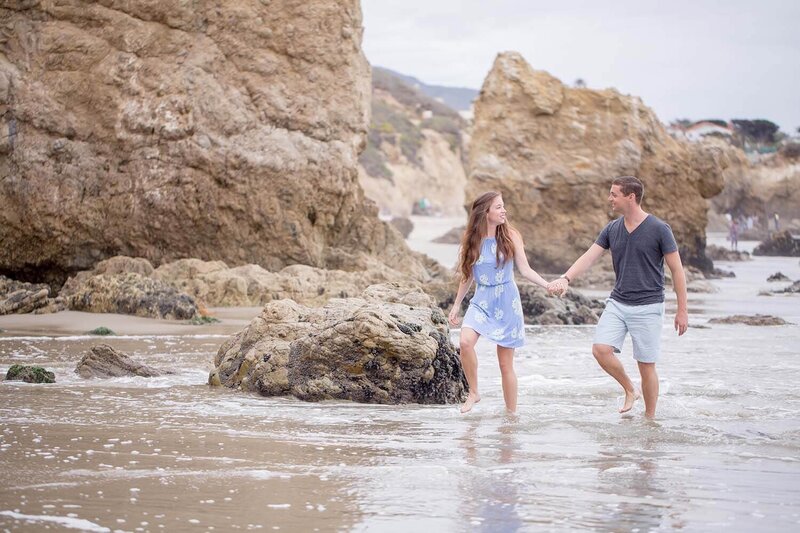 Couple walking on El Matador Beach in Malibu for their engagement shoot