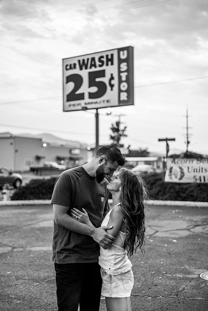 Engaged couple hugging near car wash sign